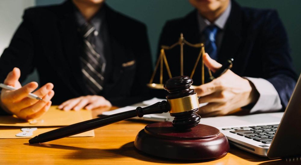 two people sitting at a table with a judge's scale and a laptop