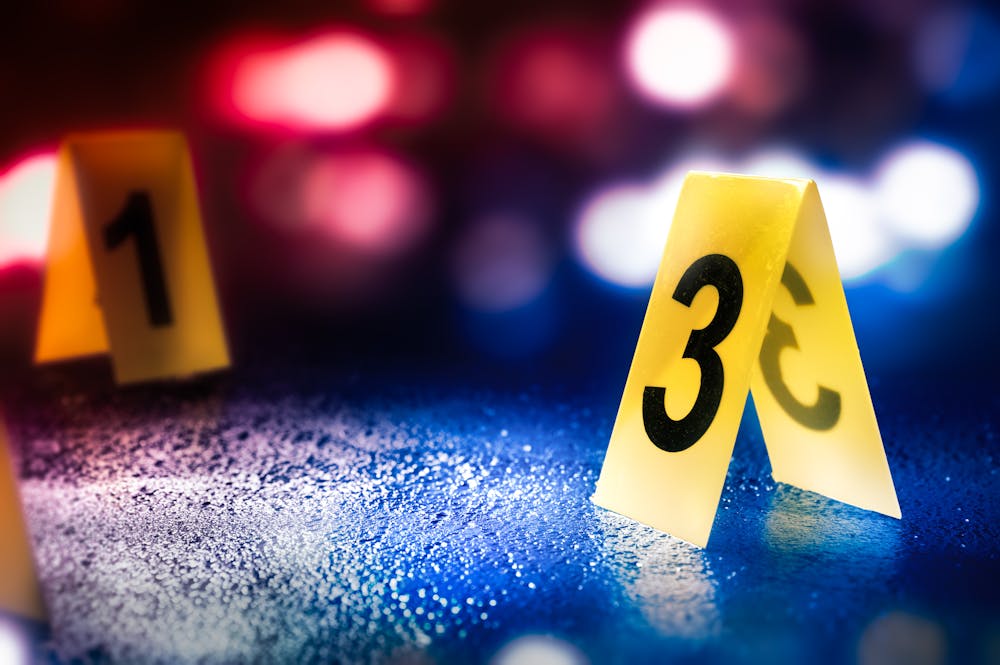 Two paper numbers, "1" and "3," are standing upright on street surface with police vehicle lights in the background